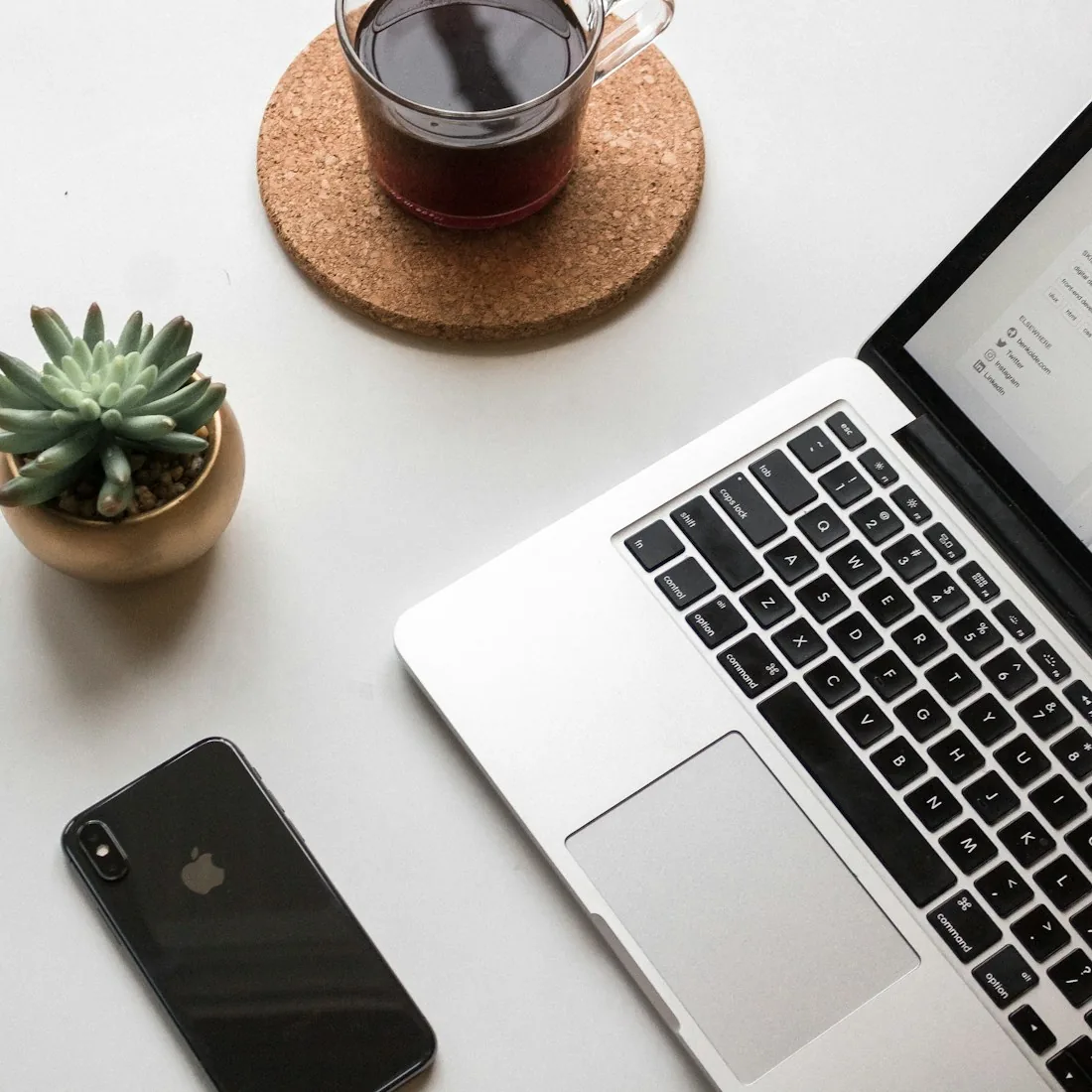 A laptop, phone and coffee on a desk